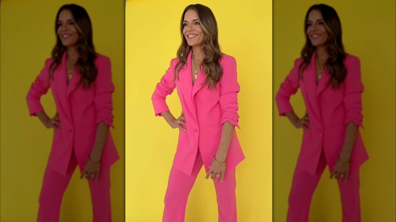 Sabrina Soto posa con un traje rosa frente a un fondo amarillo.