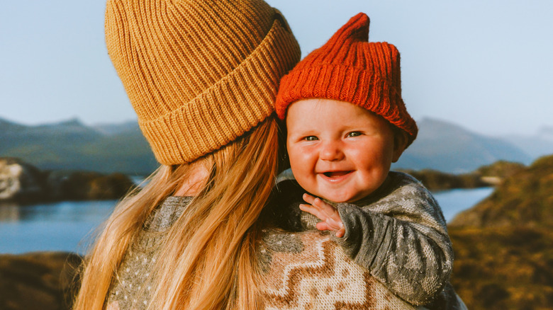 Una madre y un bebé con gorros en las montañas