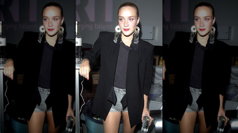 Chloë Sevigny fue fotografiada con pantalones cortos de mezclilla, camiseta negra, blazer negro de gran tamaño y aretes llamativos con el cabello peinado hacia atrás.