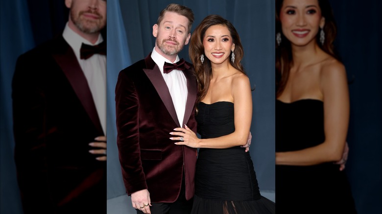 Macaulay Culkin con un traje de ante color burdeos de Paul Smith posando junto a Brenda Song con un vestido SS23 de Carolina Herrera.