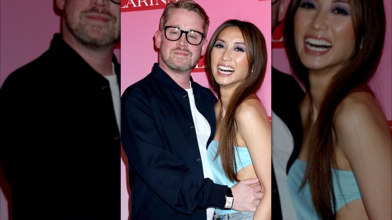 Macaulay Culkin con un botón azul marino de pie junto a Brenda Song con una blusa de tubo turquesa.