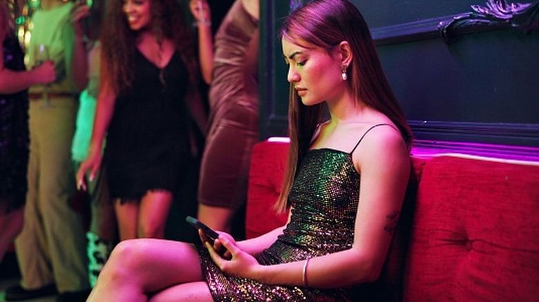 Una mujer revisa su teléfono en un club después de haber sido engañada