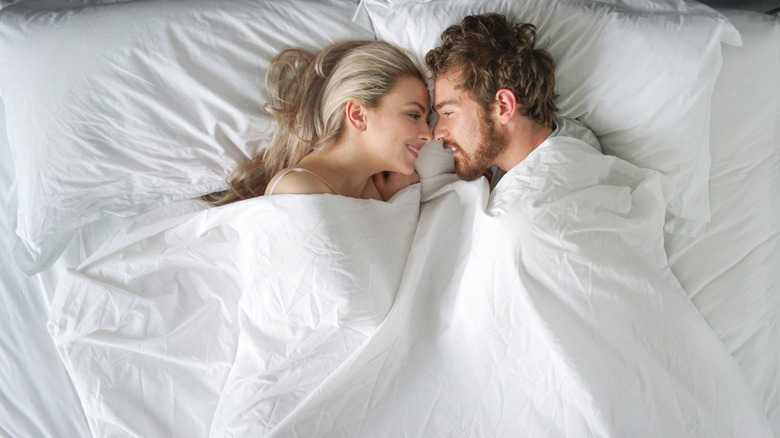 Una pareja en la cama sonriéndose