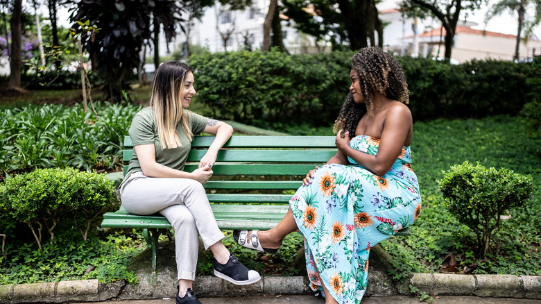 Dos mujeres hablando en un banco de un parque