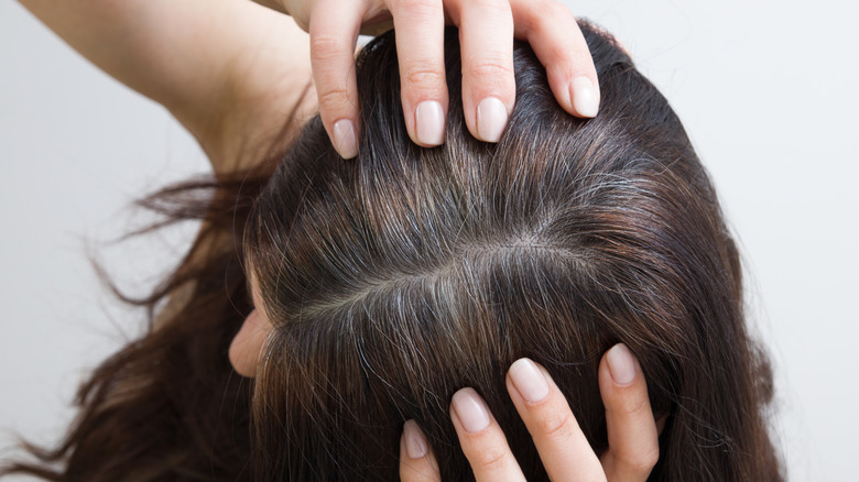 Una mujer tira de su cabello castaño grisáceo.