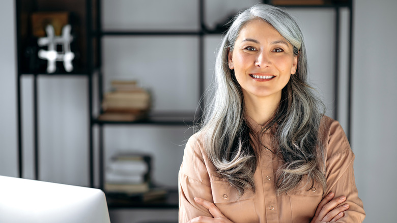 Una mujer sonríe con el pelo gris y rizado.