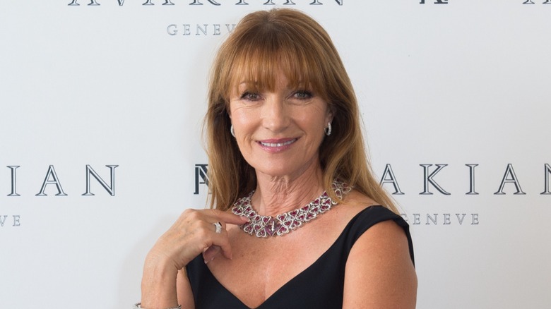 Jane Seymour en un evento de alfombra roja con un vestido negro con un collar llamativo y aretes delicados.