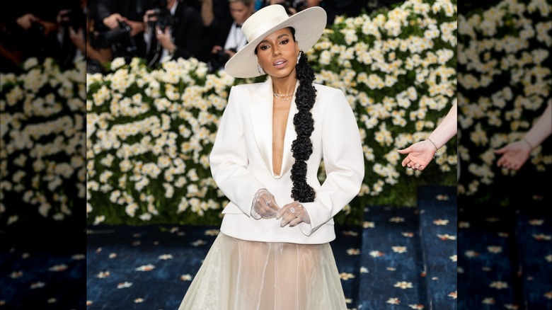 Kerry Washington posando en la Met Gala 2025 con un sombrero blanco, un top blanco con escote pronunciado y una falda de tul transparente.