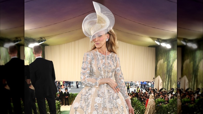 Sarah Jessica Parker posando en la Met Gala 2024 con un vestido color melocotón y un sombrero adornado.
