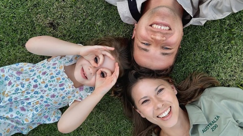 Bindi Irwin, Chandler Powell y Grace tirados en el césped