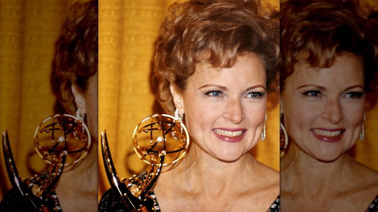 Betty White, actriz estadounidense, sonriendo mientras sostiene un premio Emmy, sobre un fondo amarillo, Estados Unidos, alrededor de 1975