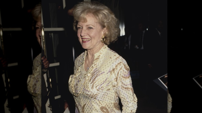 La actriz y comediante estadounidense Betty White, vestida con un vestido estampado amarillo, sonriendo mientras asiste a la quinta edición anual de los Premios Génesis, presentados por la Humane Society of the United States (HSUS) para aumentar la conciencia pública sobre las cuestiones de los derechos de los animales, celebrada en el Beverly Wilshire Hotel en Beverly Hills, California, el 3 de febrero de 1991.