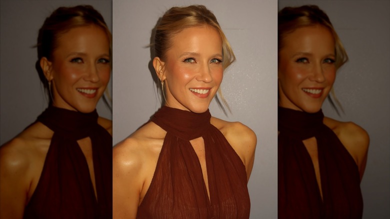 Jessy Schram sonriendo con un vestido marrón y un recogido recogido