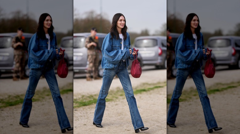Una mujer caminando con jeans bootcut y una chaqueta vaquera de gran tamaño.