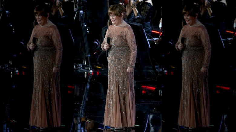Susan Boyle sostiene un micrófono con un vestido transparente adornado