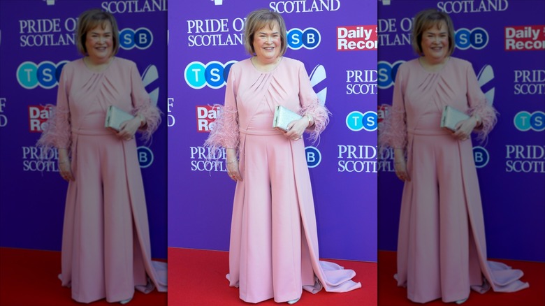Susan Boyle sonríe con un vestido rosa con puños de plumas