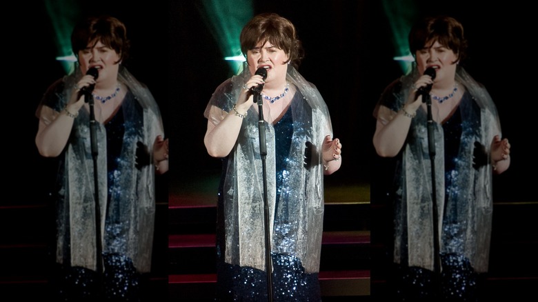 Susan Boyle canta frente a un micrófono con un vestido azul de lentejuelas