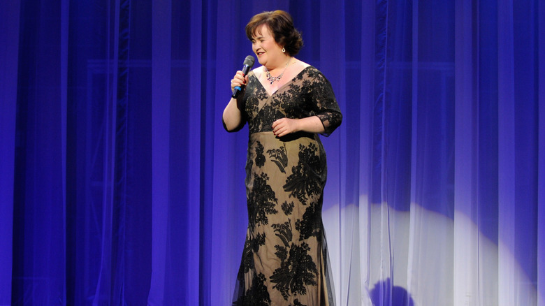Susan Boyle sostiene un micrófono con un vestido de encaje negro