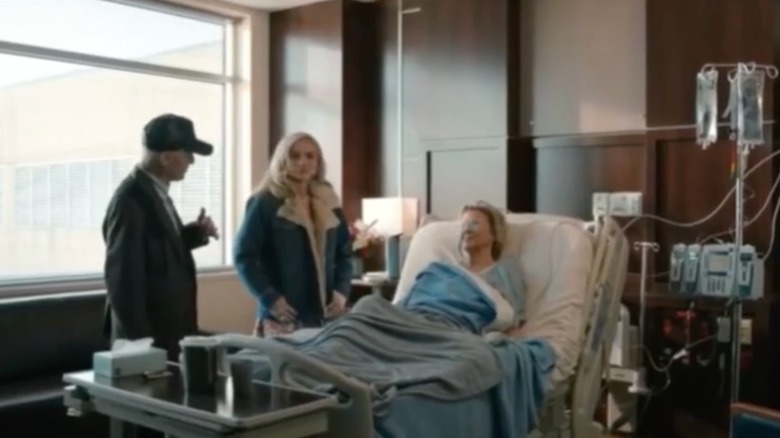 Oreana Jackson parada junto a una cama de hospital con una chaqueta vaquera con ribetes de piel en una escena de 