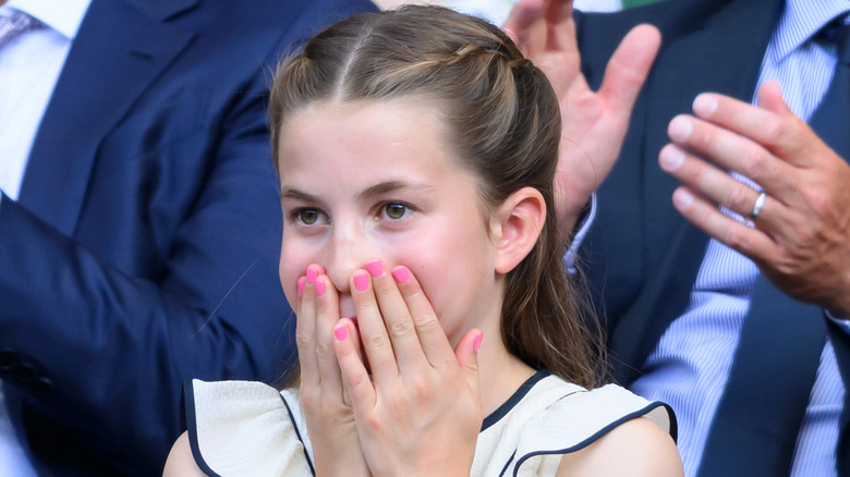La princesa Charlotte fotografiada en Wimbledon en 2025 con las manos en la boca y luciendo esmalte de uñas rosa.
