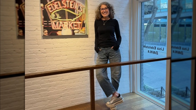 Lisa Edelstein junto a un letrero de neón de Edelstein's Market en marzo de 2026