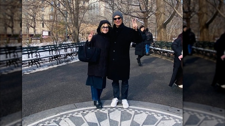 Maureen McCormick y Michael Cummings sostienen carteles de la paz en el aire afuera