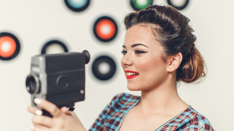 Mujer retra sosteniendo una cámara de 8 mm
