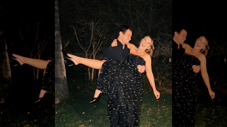 Chandler Powell sosteniendo a Bindi Irwin que lleva un vestido sin tirantes.