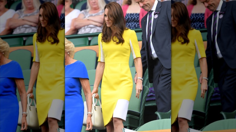 Kate Middleton con un vestido amarillo con detalles en blanco y un bolso blanco en Wimbledon en 2016.