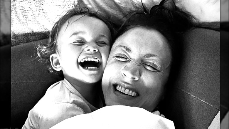 Kaley Cuoco y su hija Matilda se ríen juntas mientras están acurrucadas en una foto en blanco y negro.