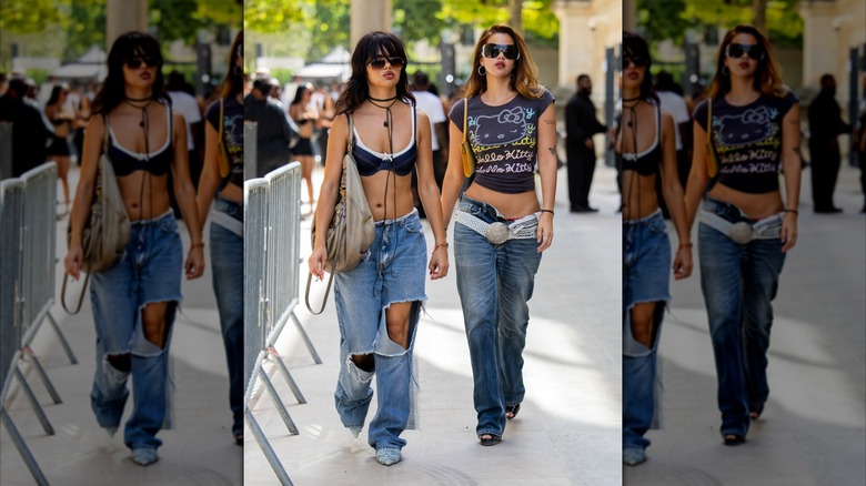 Dos mujeres caminan por una calle de París. Uno de ellos lleva unos vaqueros muy desgastados.