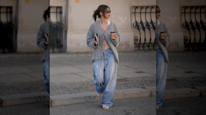 Una mujer que vestía unos vaqueros holgados y un cárdigan gris parcialmente abotonado.