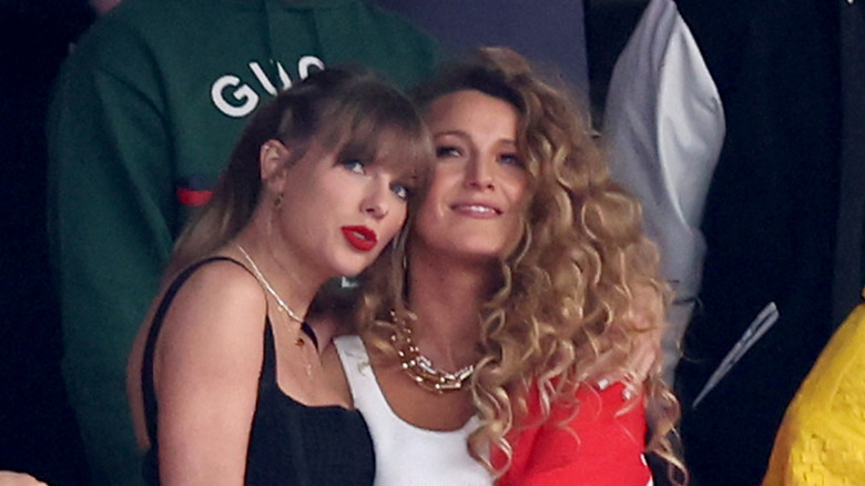 Taylor Swift con un conjunto negro con labios rojos y Blake Lively con una camisa blanca y el pelo muy rizado en el Super Bowl.