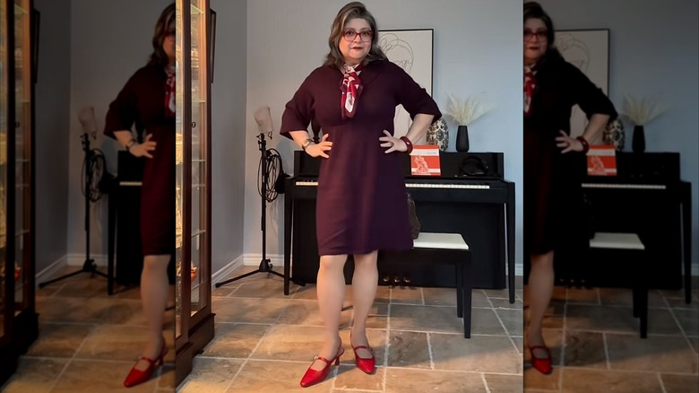 Una mujer con un vestido morado oscuro, zapatos rojos brillantes y una bufanda estampada.