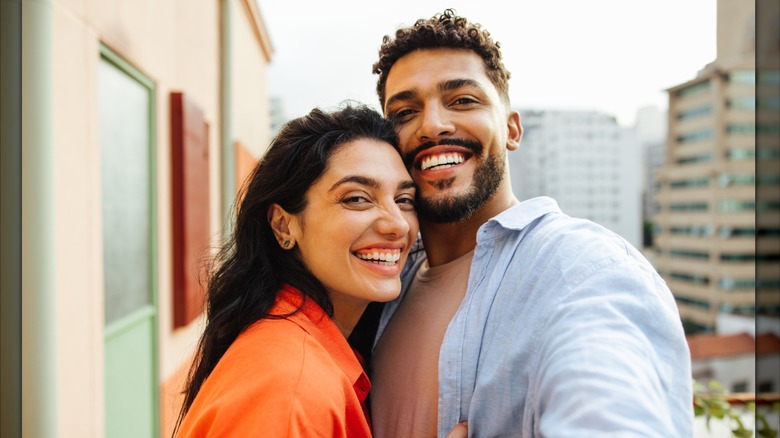 Una pareja posa para un selfie sonriendo juntos.