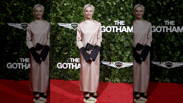 Laurie Metcalf posando en una alfombra roja con un vestido de satén rosa con mangas parcialmente negras.