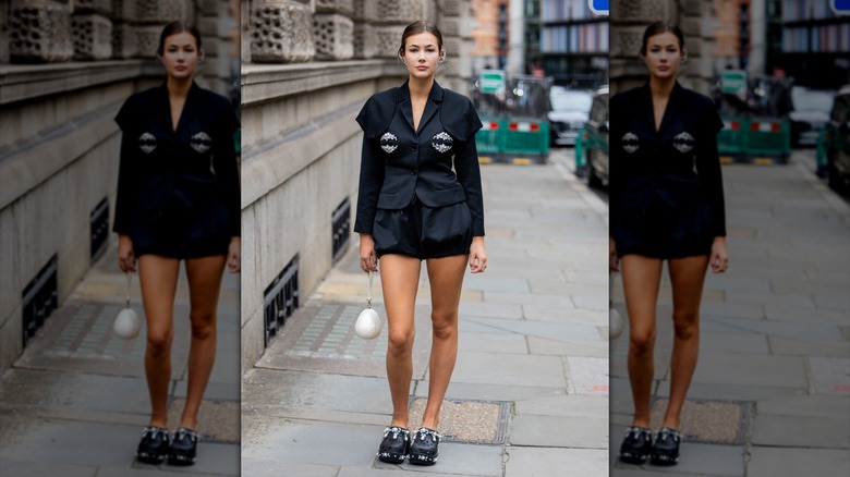 Una mujer vestida con deslumbrantes Crocs y una chaqueta negra.