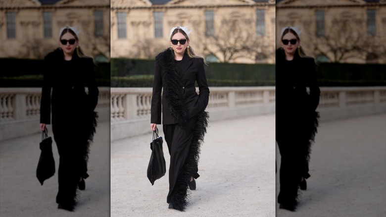 Una mujer vestida con un traje negro con adornos de plumas.