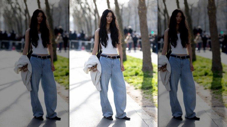 Una mujer con jeans holgados y una camiseta sin mangas.