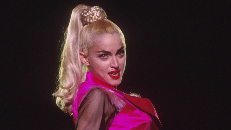 Madonna actúa con un traje rosa y una coleta alta.