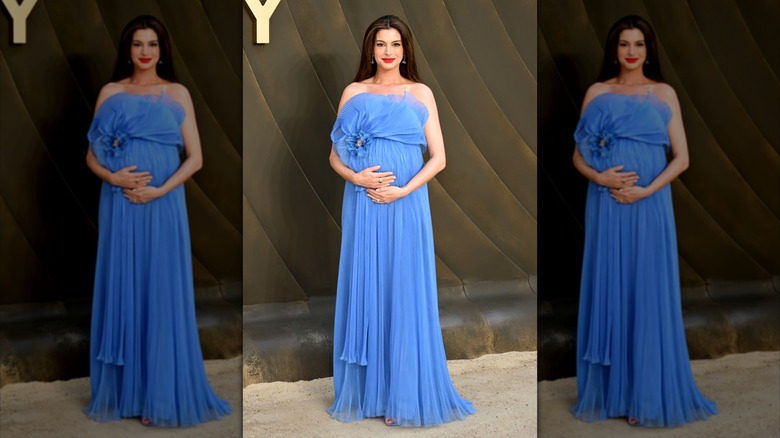 Anne Hathaway se pone las manos en la barriga con un vestido azul