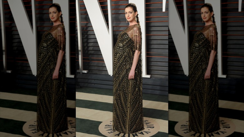 Anne Hathaway posa con un vestido negro y dorado que deja ver su panza