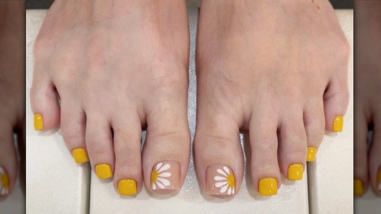 Primer plano de una pedicura en color amarillo mostaza con puntera decorativa en forma de margarita