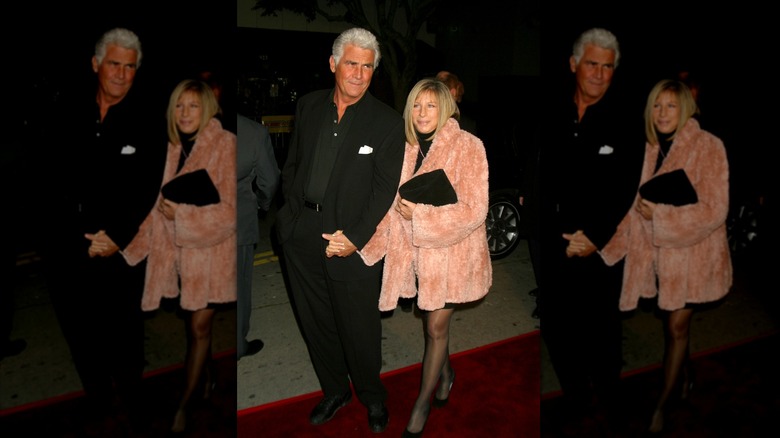 Barbra Streisand con un abrigo rosa difuso de la mano de su esposo James Brolin con un traje completamente negro.
