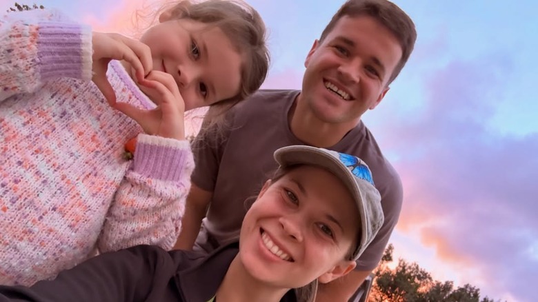 Bindi Irwin, Chandler Powell y su hija Grace Warrior Irwin Powell sonríen para una selfie familiar