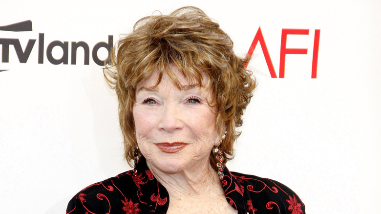 Shirley MacLaine posando con un vestido negro con diseños rojos en la 40ª ceremonia del AFI.