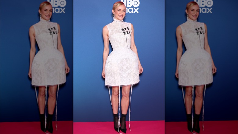 Diane Kruger en la alfombra roja con un vestido corto de encaje blanco y botas negras.