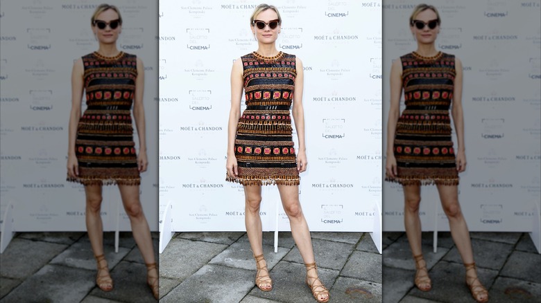Diane Kruger en un evento con un minivestido con un intrincado estampado de rayas y gafas de sol.