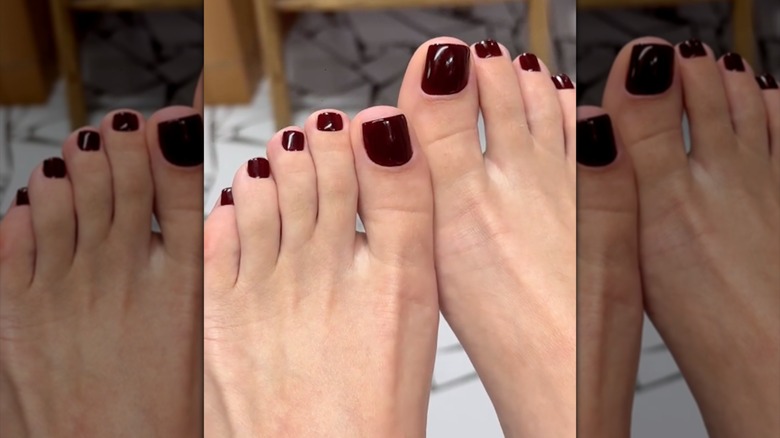 Pies descalzos con uñas de color burdeos oscuro.