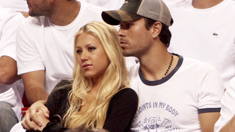 Anna Kournikova y Enrique Iglesias se dan la mano mientras ven un partido de baloncesto